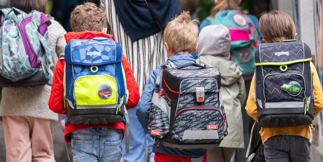 Kinder sitzen mit dem Rücken zur Kamera in einem Klassenzimmer