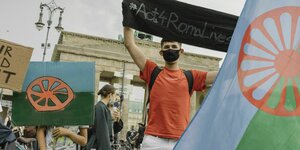 Bei einer Demo halten Gruppen Flaggen der Roma