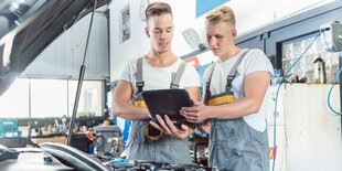 Zwei junge automechaniker mit Labtop über einer Kühlerhaube