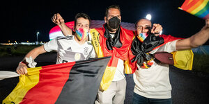 Drei deutsche Fußballfans mit etlichen Flaggen