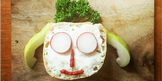 Auf eine Scheibe Brot hat jemand mit Gemüse ein Gesicht gelegt