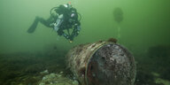 Ein Taucher untersucht einen Munitionsrest unter Wasser