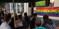 Fans beim Public viewing in Bonn "fuck UEFA" auf einer Regenbogenfahne unter der Fußballübertragung auf der STrasse
