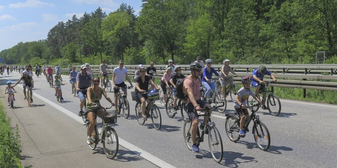 Bei einer Fahrraddemo fahren Menschen auf einer Autobahn mit dem Fahrrad