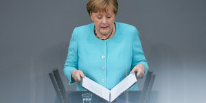 undeskanzlerin Angela Merkel (CDU) klappt nach der Regierungserklärung zum bevorstehenden EU-Gipfel bei der Sitzung des Deutschen Bundestags das Redemanuskript zu