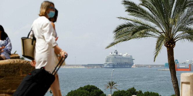 Kreuzfahrer im Hafen, davor Touristinnen mit Rollkoffer