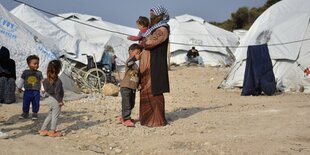 Frau mit Kleinkindern vor Zelten im Sand