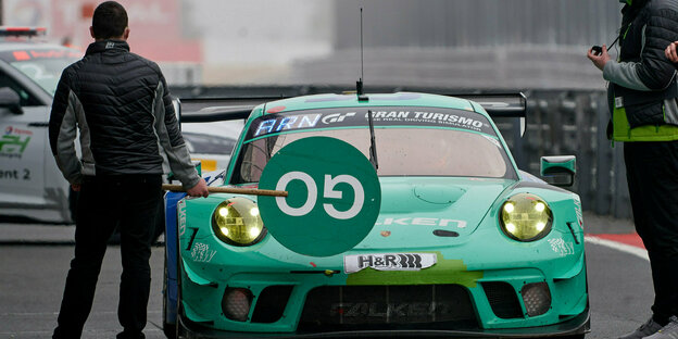 Grüner Porsche steht am Boxenstopp mit Schild "Go"