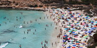 Ein strand voller Sonneschirme und jede Menge Badende in türkisblauem Wasser