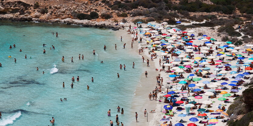 Ein strand voller Sonneschirme und jede Menge Badende in türkisblauem Wasser