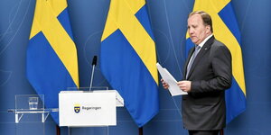 Schwedens Ministerpräsident Stefan Löfven geht vor Schweden-Flaggen zu einem Rednerpult