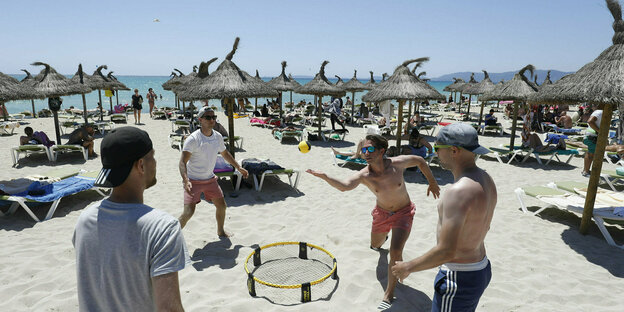 Männer spielen am Strand Spikeball