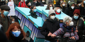 Aktivisten stecken während einer Demonstration in Bussen aus Pappe, um einen kostenlosen ÖPNV zu fordern - alle Demo-TeinehmerInnen tragen Mund-Nasenschutz