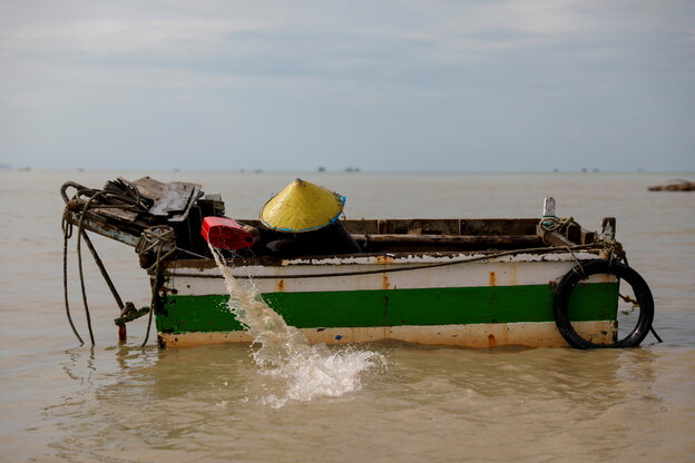 Ein Fischer kippt Wasser aus seinem Boot.