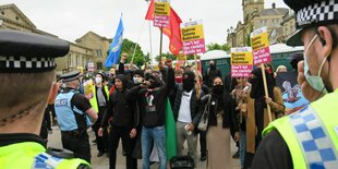 Polizeibeamte und Demonstrierende mit Schildern mit der Aufschrift Oppose Tommy Robinson - Don't let the racists divide us