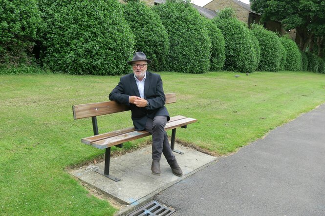 George Galloway sitzt auf einer Parkbank