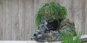 Ein Soldat mit grüner Tarnung zielt mit einem Sturmgewehr