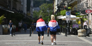 Zwei niederländische Fußballfans, mit Nationalflaggen eingehüllt, gehen durch die Innenstadt von Budapest, Ungarn