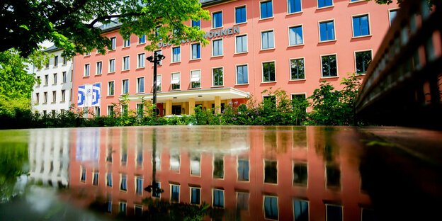 Die Fassade der Zentrale Wohnungsgesellschaft Deutsche Wohnen in Berlin spiegelt sich in einer nassen Tischtennisplatte
