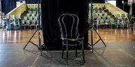 Leerer Theatersaal mit Stuhl auf der Bühne, abgeschirmt durch einen schwarzen Vorhang