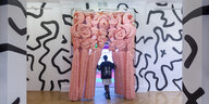 Durch einen rosafarbenen Gummivorhang betritt eine Frau einen Ausstellungsraum