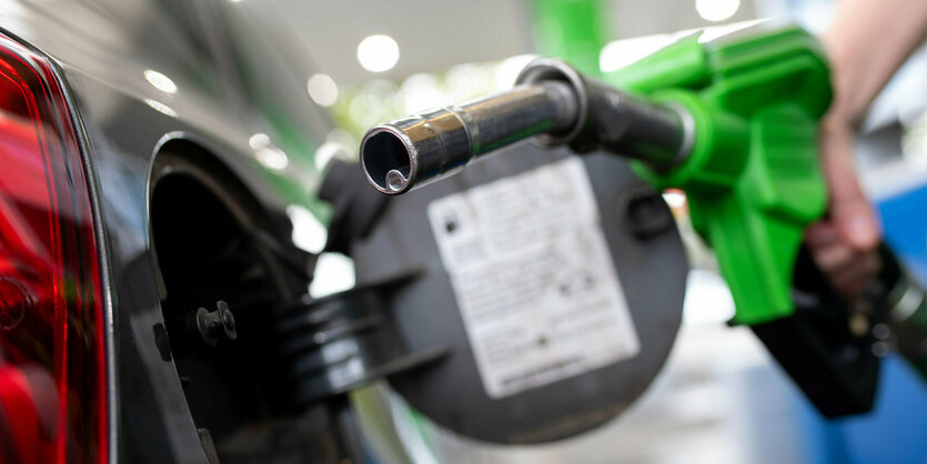 Bayern, München: Eine Frau hält an einer Tankstelle an einer Zapfsäule eine Zapfpistole in der Hand und betankt ein Auto.