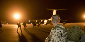 Im Scheinwerferlicht laufen Soldaten nachts auf ein Transportflugzeug zu