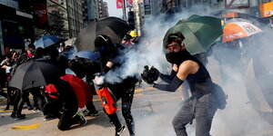 DemonstrantInnen stehen imt Regenschirmen auf den Straßen Hongkongs