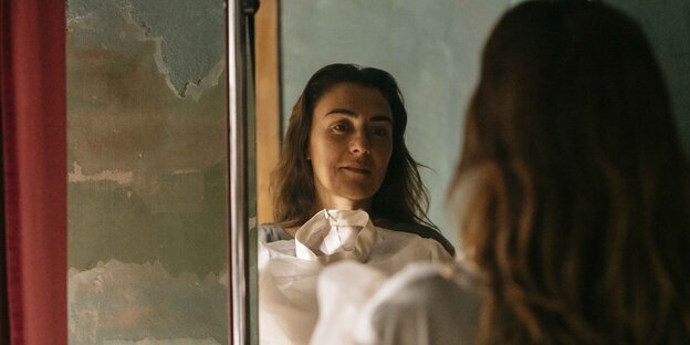Rosa (Candela Peña) hält vor einem Spiegel ein Hochzeitskleid an.
