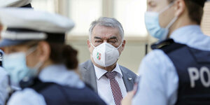 ordrhein-Westfalens Innenminister Herbert Reul traegt Mund-Nasenschutz mit NRW Logo - vor ihm PolizistInnen