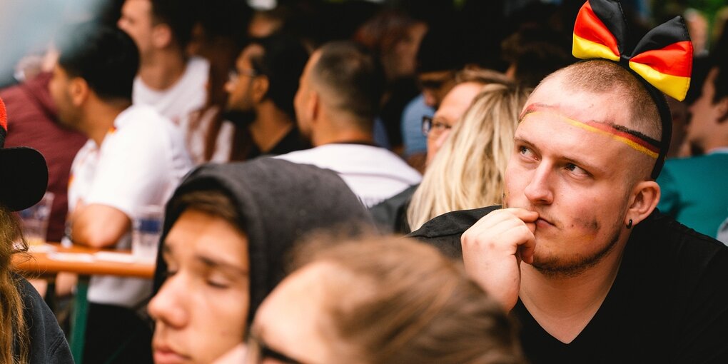 Zuschauer beim Public Viewing, einer trägt eine schwarz-rot-goldene Fliege auf dem Kopf