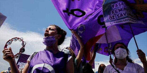 Demonstrantinnen mit violetten Flaggen und einem Tambourine