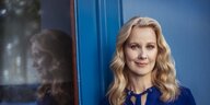 Autorin und Journalistin Nicole Diekmann steht vor einer blauen Wand und blickt in die Kamera