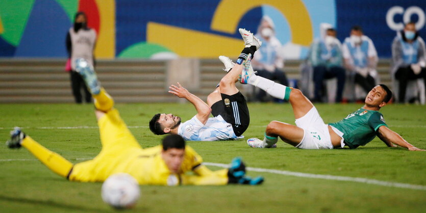 Bolivien Roberto Fernandez und der Argentinier Sergio Aguero sitzen auf dem Rasen und schauen dem Ball nach