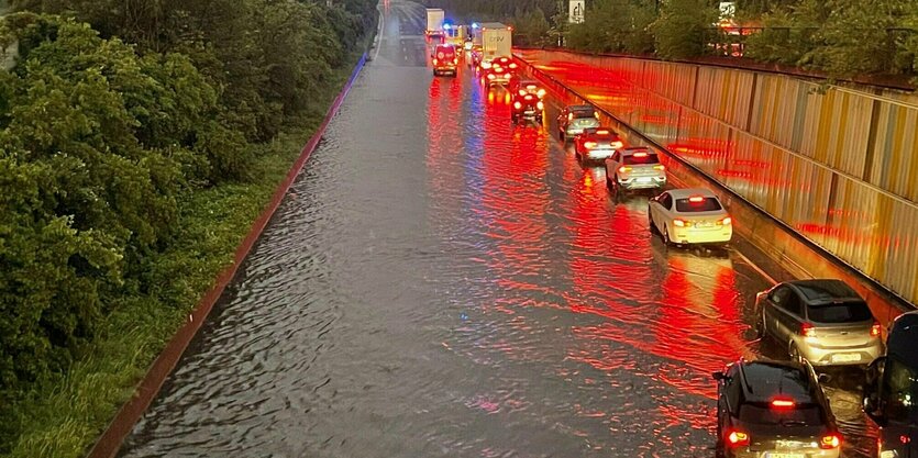 Rücklichter spiegeln sich im Wasser, das eine Strasse überflutet hat