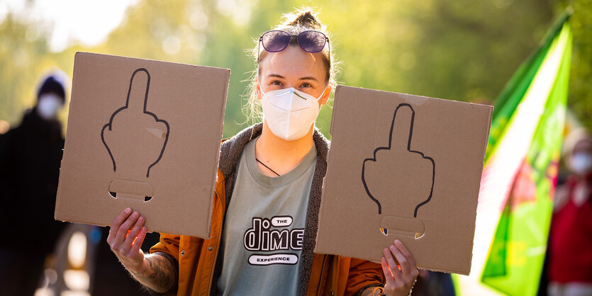 Demonstrantin mit Mittelfinger Schildern