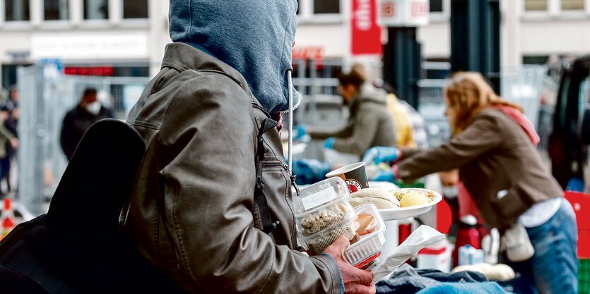 Junger Mensch im Kaputzenpullover mit Essens-Schalen