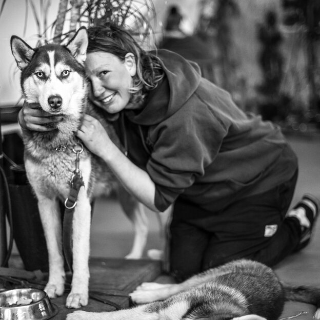 Porträt einer jungen Frau, die mit einem Husky kuschelt Porträt einer jungen Frau, die mit einem Husky kuschelt