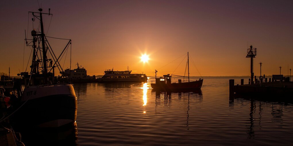 Ein Kutter fährt kurz nach Sonnenaufgang in den Hafen auf der Ostseeinsel Hiddensee