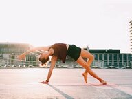 Eine junge Frau in einer schwierig aussehenden Yoga-Pose Eine junge Frau in einer schwierig aussehenden Yoga-Pose