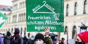 Eine Demonstrantin hält ein Schild hoch.