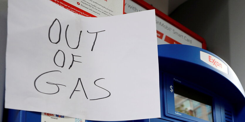 Hangeschriebenes Schild "out of gas" an einer Tankstelle