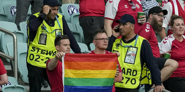 Zwei dänische Fans mit einer LGBTIQ-Fahne, dahinte zwei Orner