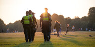 Polizisten patroullieren auf einer Wieser im Stadtpark