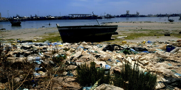 ein Boot, im Vordergrund Müll, im Hintergrund Wasser