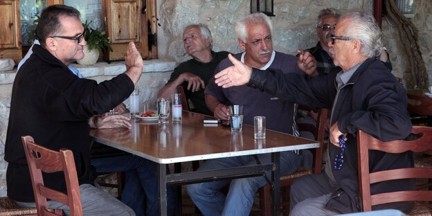 Männer sitzen an einem Tisch in einem Cafe Männer sitzen an einem Tisch in einem Cafe