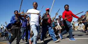 Demonstrierende Männer mit Stöcken auf dem Weg zum Haus des früheren Präsidenten von Südafrika Jacob Zuma