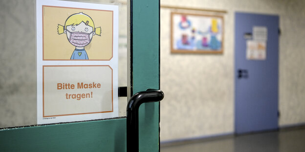 Glastür in einem Schulgebäude, mit Plakat "Masken tragen"