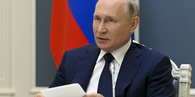 Russlands Staatspräsident Putin an einem Tisch sitzend