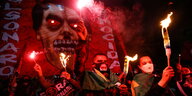 Demonstierende mit Fackeln und einem Banner, das Jair Bolsonaro als einen Dämon mit rot leuchtenden Augen zeigt